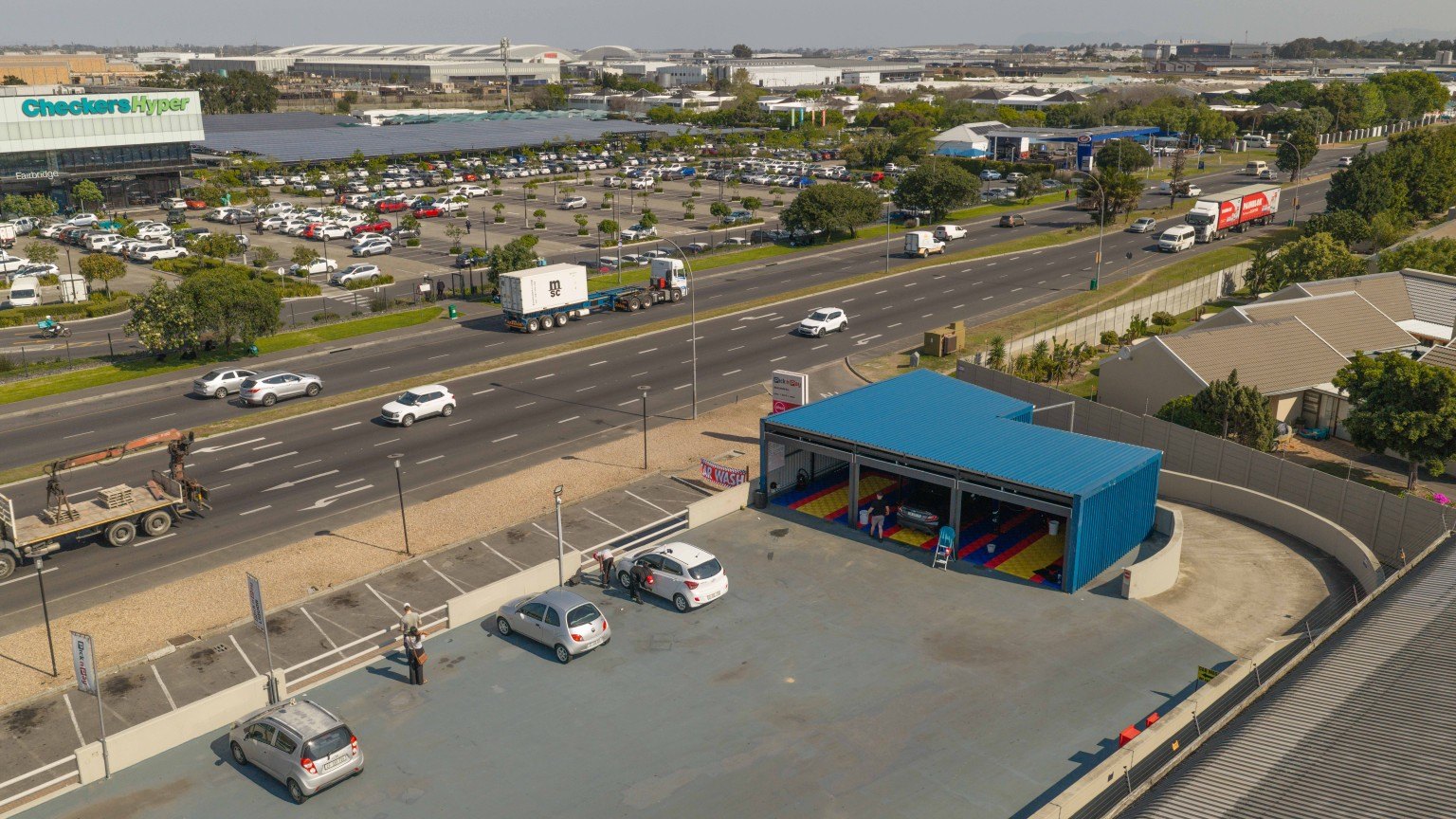 Aerial view of Kwikky's blue-roofed wash bays and spacious rooftop parking area